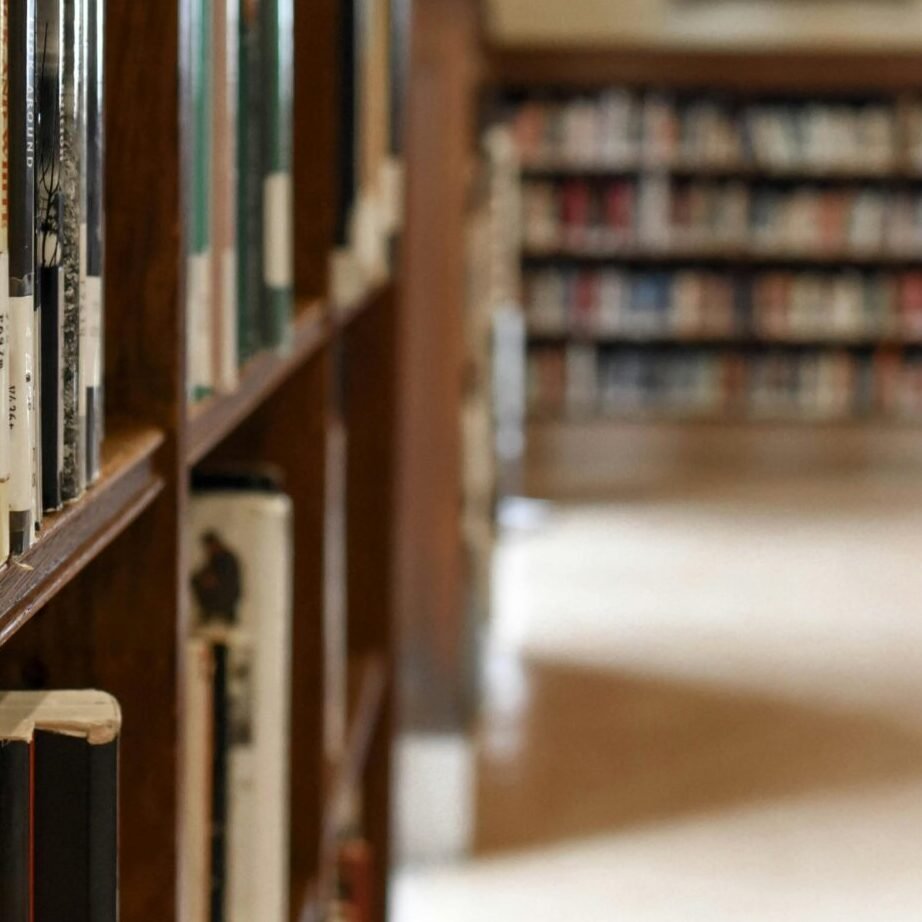 A quiet library interior featuring bookshelves, seating, and a study area for learning and reading.