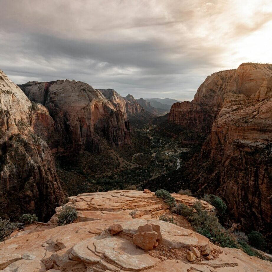 Capture of the dramatic Zion National Park cliffs during a tranquil sunset with a cloudy sky.