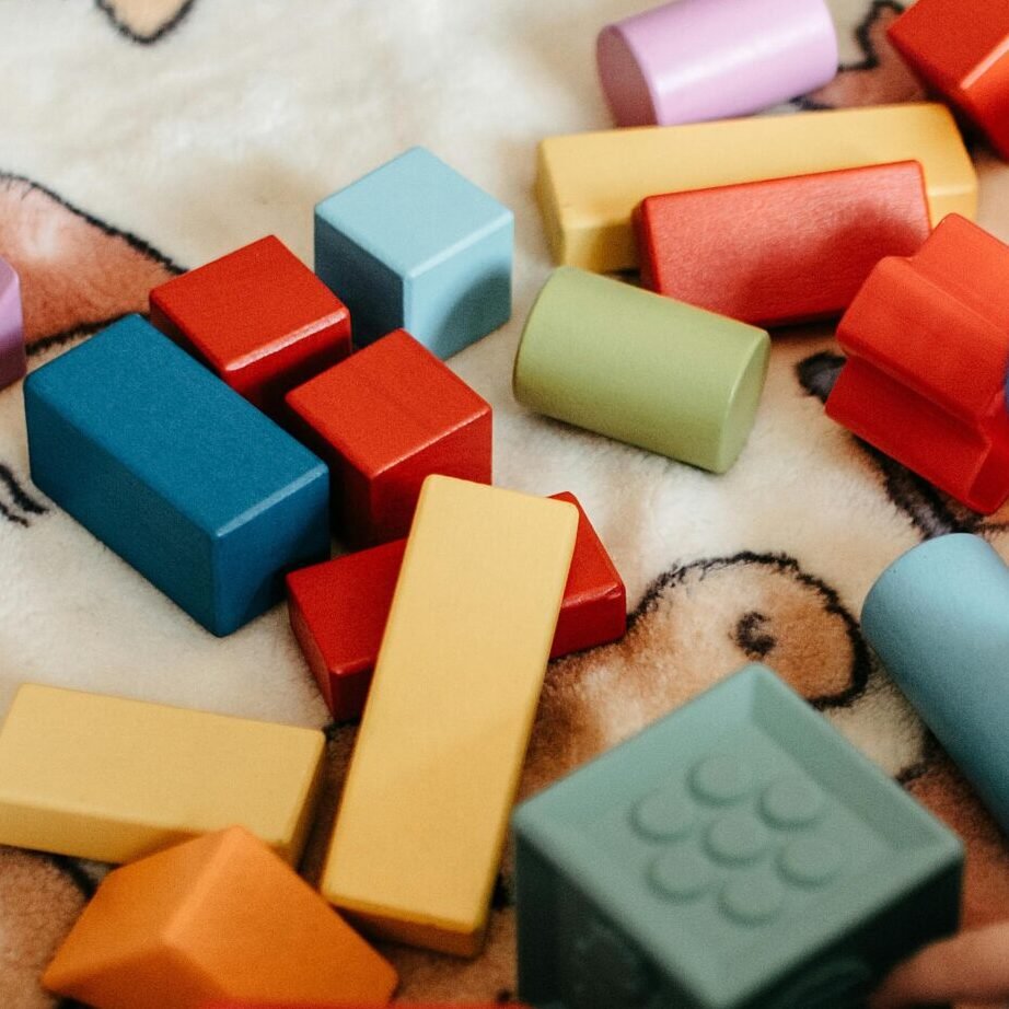 A toddler joyfully playing with a variety of colorful building blocks on a patterned blanket.